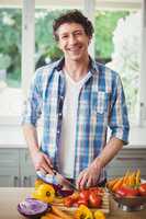 Portrait of smiling man cutting vegetables at home