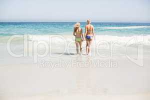 Two rear women walking on the beach