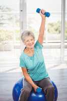 Portrait of smiling senior woman holding dumbbell