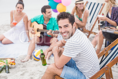 Happy man holding beer and smiling while sitting with his friend