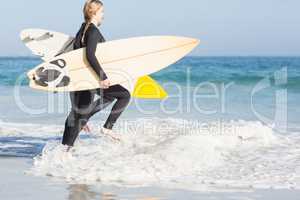 Woman with surfboard running towards sea