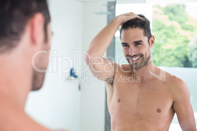 Shirtless young man smiling while looking in mirror