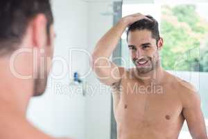 Shirtless young man smiling while looking in mirror