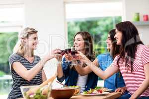 Smiling friends toasting red wine glasses