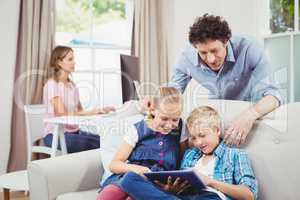 Children using digital tablet while father looking at them