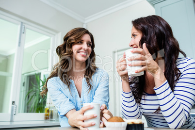 Smiling friends holding coffee mugs at table