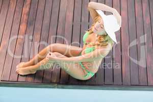 Beautiful woman in green bikini sitting by pool side