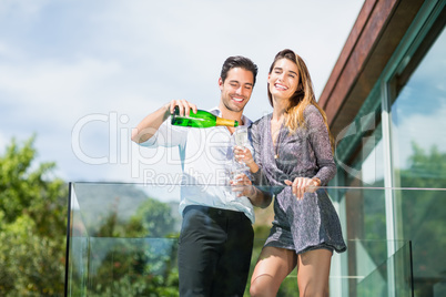 Cheerful couple drinking champagne at balcony