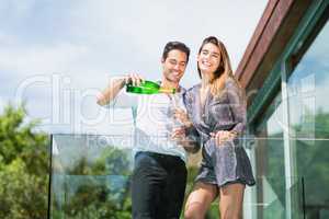 Cheerful couple drinking champagne at balcony