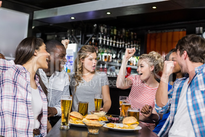 Happy friends having a drink and watching sport