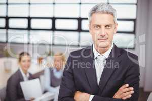 Confident businessman with colleagues in background