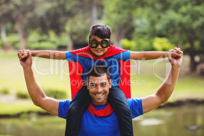 Boy in superhero costume sitting on fathers shoulder