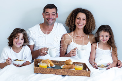 Portrait of family having breakfast in bed