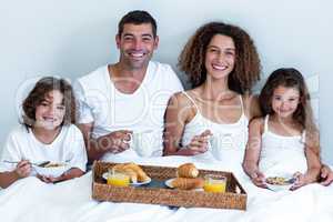 Portrait of family having breakfast in bed