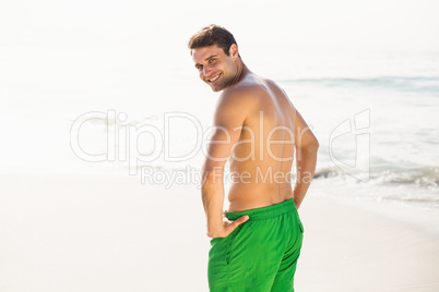 Portrait of man in swim shorts standing on beach