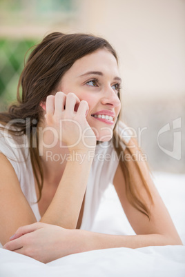 Thoughtful smiling woman lying on bed