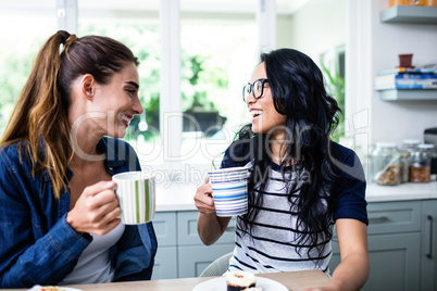 Young female friends laughing while drinking coffee