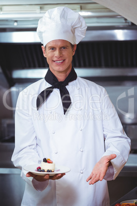 Proud chef holding a plate of cheesecake desert