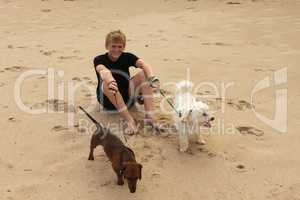 Boy Sitting on Beach with Dogs