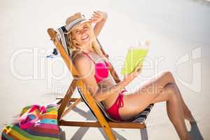 Woman in bikini sitting on armchair and reading book