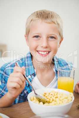 Happy boy having breakfast at table in house
