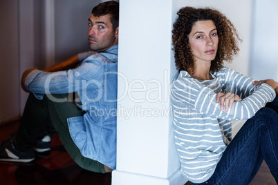 Portrait of couple sitting on opposite sides of the wall