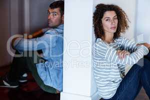 Portrait of couple sitting on opposite sides of the wall