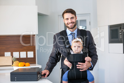 Confident businessman carrying daughter by table