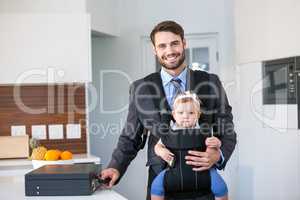 Confident businessman carrying daughter by table