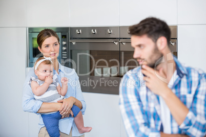 Woman with baby looking at tensed husband