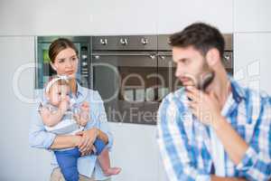 Woman with baby looking at tensed husband