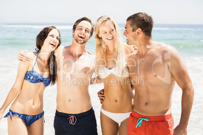 Happy friends standing and talking together on the beach