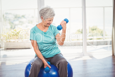 Smiling senior woman holding dumbbell