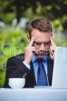 Businessman using laptop having a headache