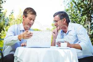 Two businessmen meeting in a restaurant using laptop