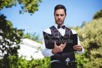 Handsome waiter looking at the menu