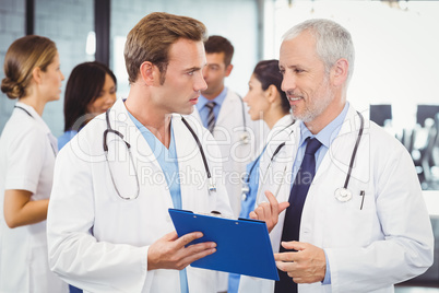 Two doctors looking at clipboard and discussing in hospital