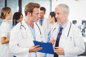 Two doctors looking at clipboard and discussing in hospital