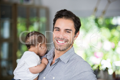 Portrait of cheerful father carrying baby