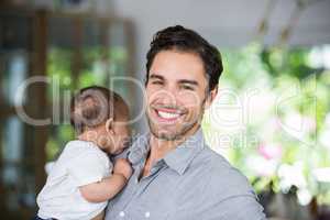 Portrait of cheerful father carrying baby