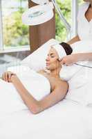 Woman relaxing while receiving facial massage