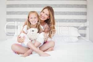 Portrait of happy mother with daughter on bed
