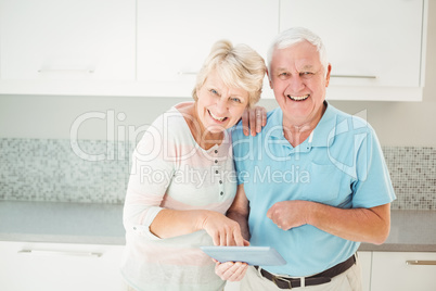 Portrait of senior couple laughing with tablet in kitchen