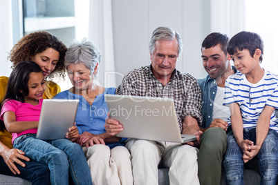 Happy family using laptop and digital tablet in living room