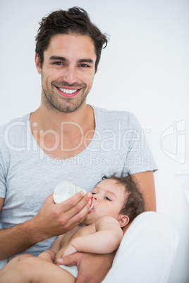 Man feeding milk to baby girl