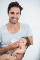 Man feeding milk to baby girl