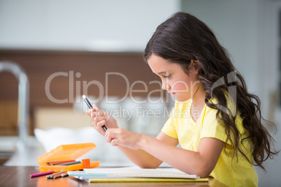 Girl holding pen while sitting at desk