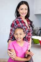 Young woman standing with her daughter in kitchen