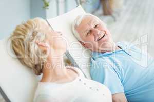High angle view of happy senior couple relaxing on lounge chair