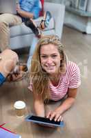 Young woman using digital tablet while lying on floor